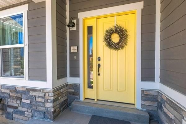 Yellow front door and porch on home with vinyl siding